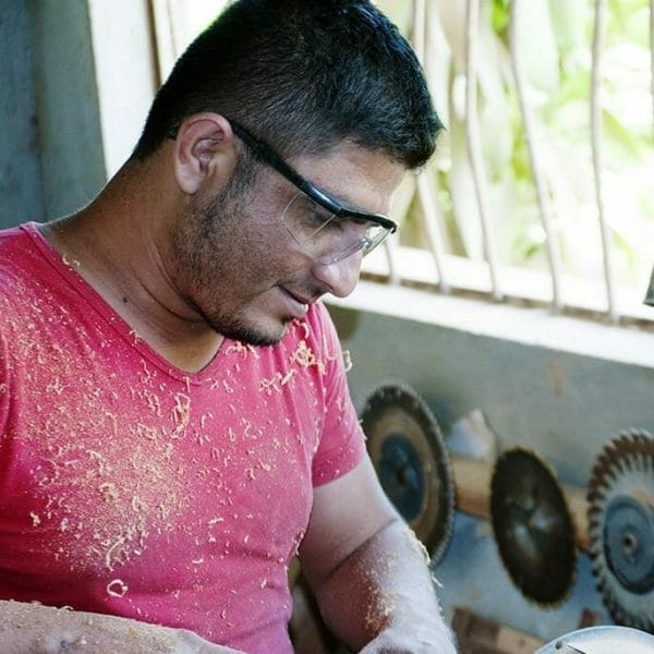 Hector, an Itza Wood carpenter, wears safety goggles as he creates handcrafted wooden gifts