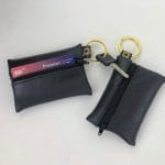 Two mini coin bag keychains with zippers, made from upcycled materials