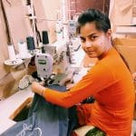 woman at sew mach in orange sweater