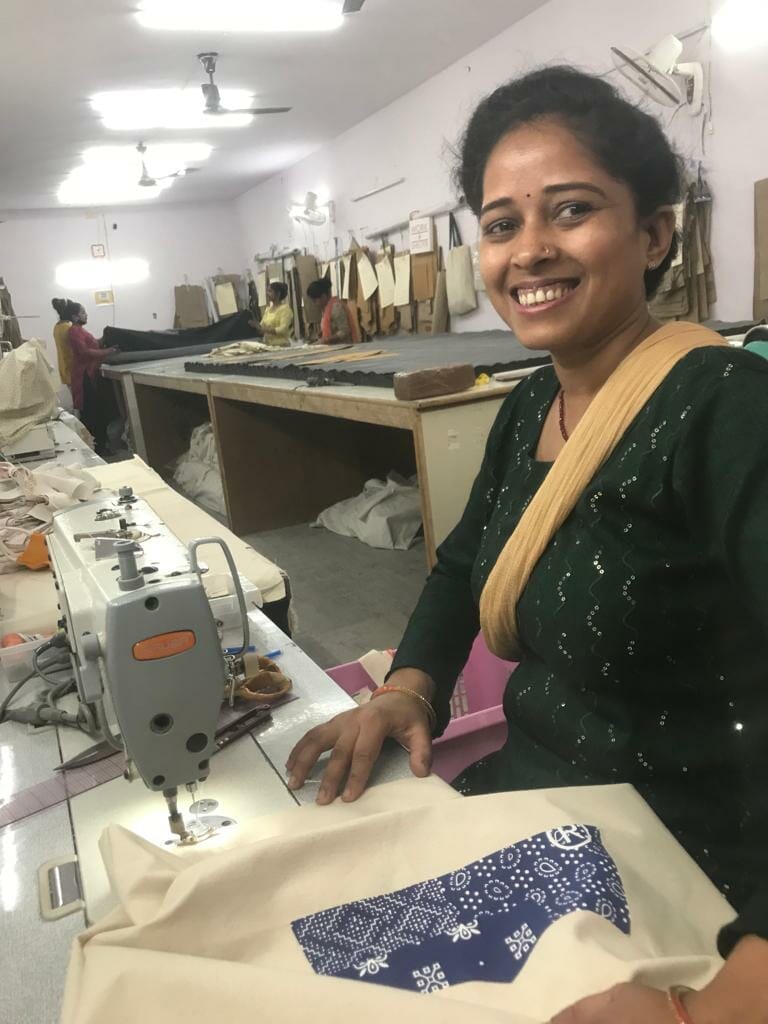 Rita smiles as she sews reusable shopping bags at the Work+Shelter studio.