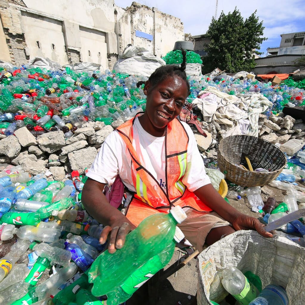 PbP custom water bottles with logo recycled come from collectors like the one pictured here among piles of plastic bottles