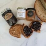 Our jam and honey gift set includes berry preserves, nut butter, and honey, which can be enjoyed spread on toast or bagels as shown in this overhead shot.