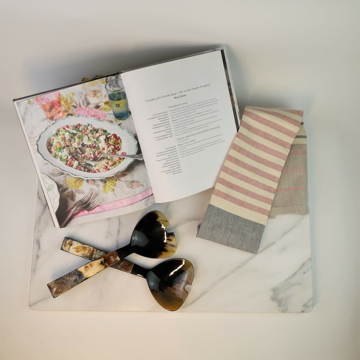 Overhead look at the Share the Season cookbook gift basket, with SHARE cookbook, tea towel, and salad tongs.