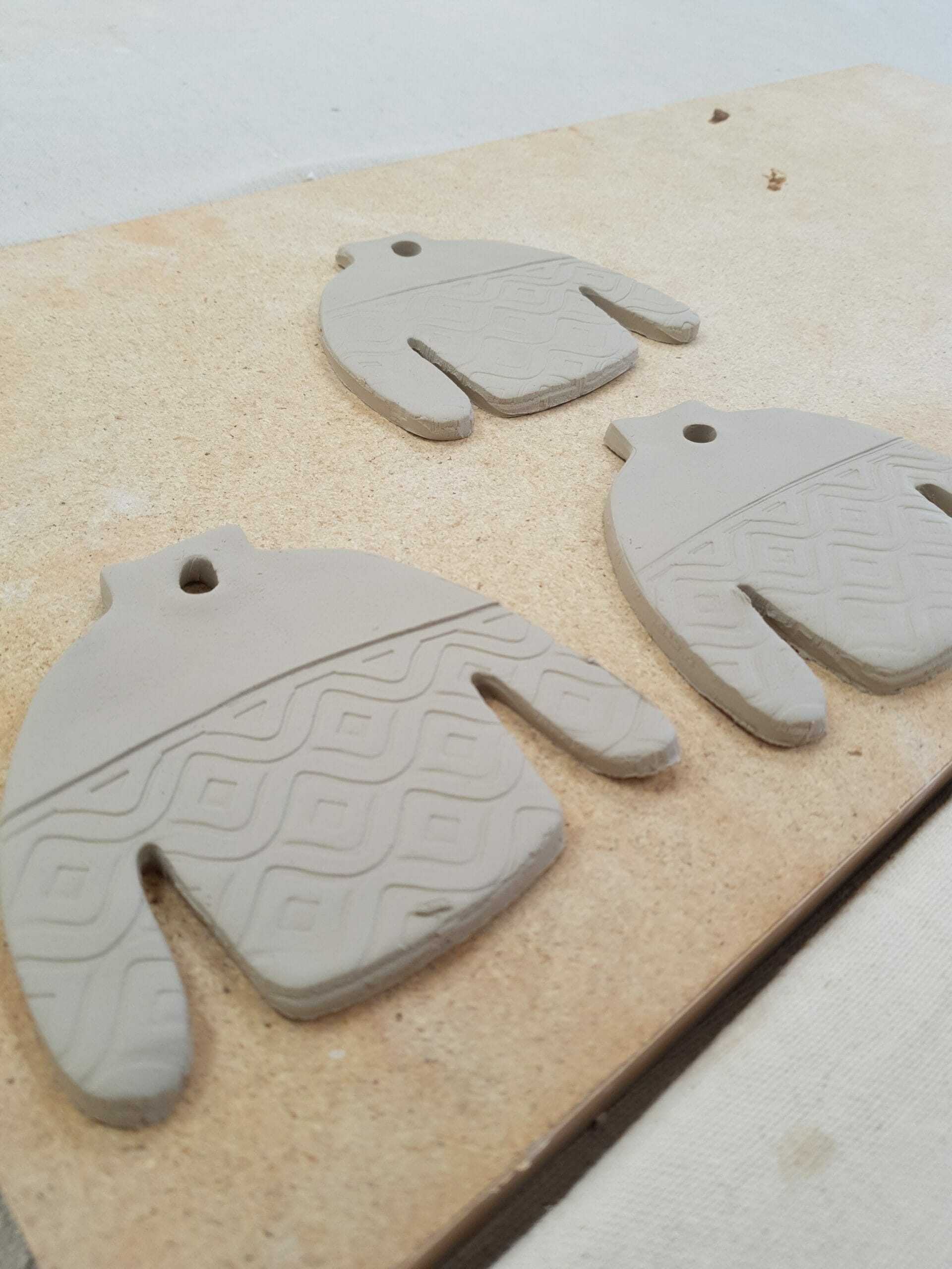 Three ugly sweater ornaments lie on a table before being glazed and fired Three ugly sweater ornaments lie on a table before being glazed and fired