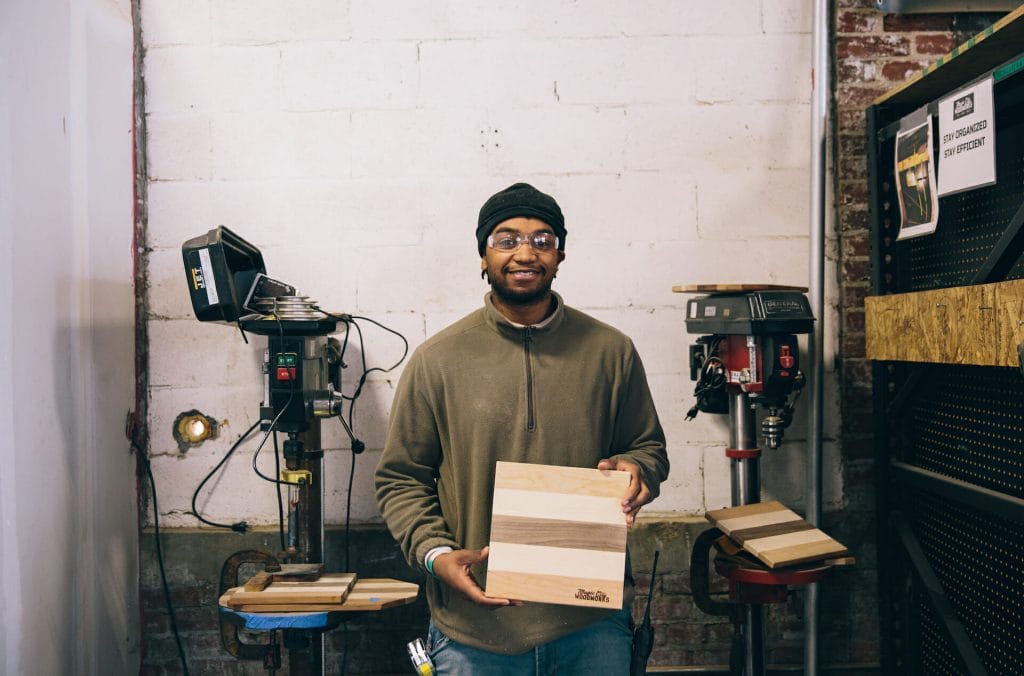 An apprentice proudly shows one of the branded cutting boards he helped create