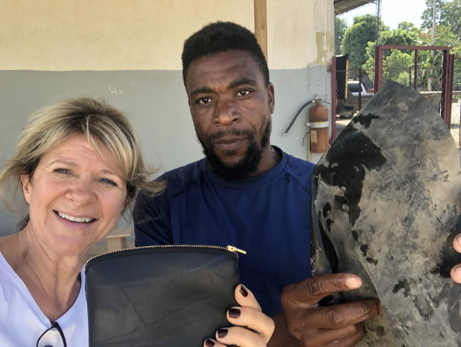 Peace by Piece International founder Lauri Pastrone holds up a leather bag next to a craftsman from Deux Mains