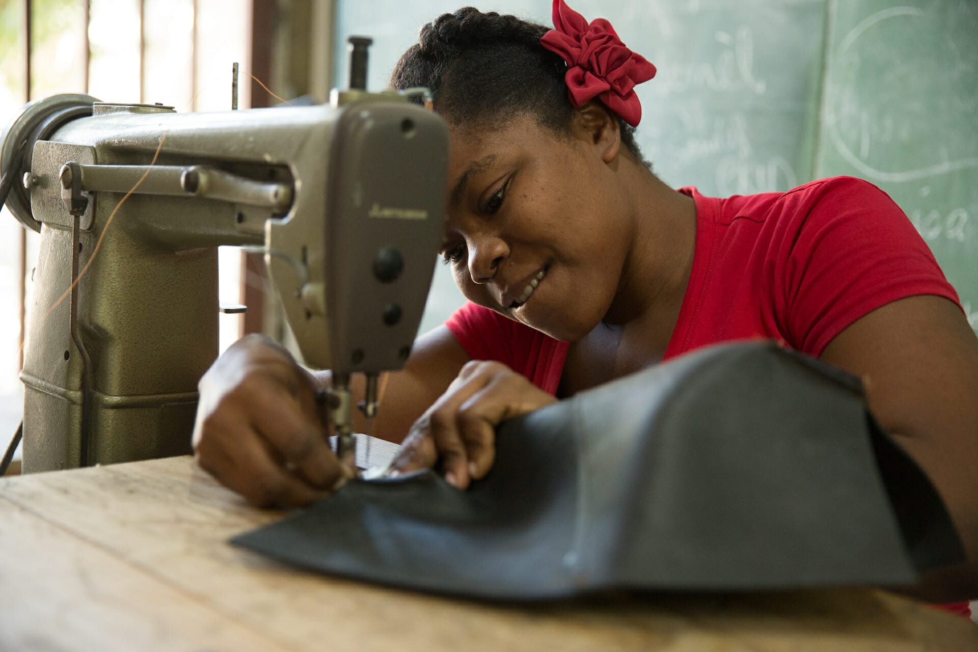 A woman stitches leather gifts from Haiti at a sewing machine